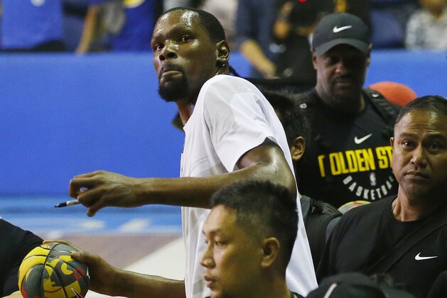 Kevin Durant of the Golden State Warriors and the NBA Finals Most Valuable Player, throws an autographed basketball to his fans following an exhibition basketball game with Philippine basketball players at the Smart Araneta Coliseum northeast of Manila, Philippines, Sunday, July 8, 2018. Durant is in the Philippines for the second time to conduct basketball clinics and to launch his Nike 'KD 11' basketball shoes. (AP Photo/Bullit Marquez)