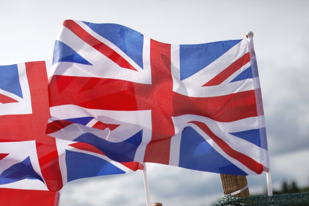 A boy attaches a British flag to a barrier at the rowing venue in Eton Dorney, near Windsor, England, at the 2012 Summer Olympics, Monday, July 30, 2012. (AP Photo/Natacha Pisarenko)