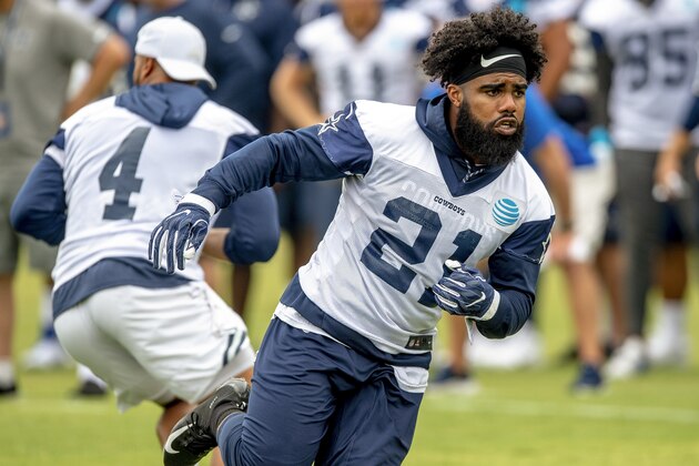 Dallas Cowboys running back Ezekiel Elliott (21) runs by teammate quarterback Dak Prescott (4) after faking the handoff during the team's NFL football training camp, Thursday, July 26, 2018, in Oxnard, Calif. (AP Photo/Gus Ruelas)