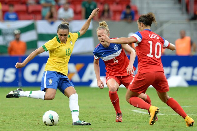 Brazilian player Marta (L) vies for the ball with US players Becky Sauerbrunn (C) and Carli Lloyd during their Brasilia International Tournament football match at Mane Garrincha Stadium in Brasilia, on December 14, 2014.  AFP PHOTO/EVARISTO SA        (Photo credit should read EVARISTO SA/AFP/Getty Images)