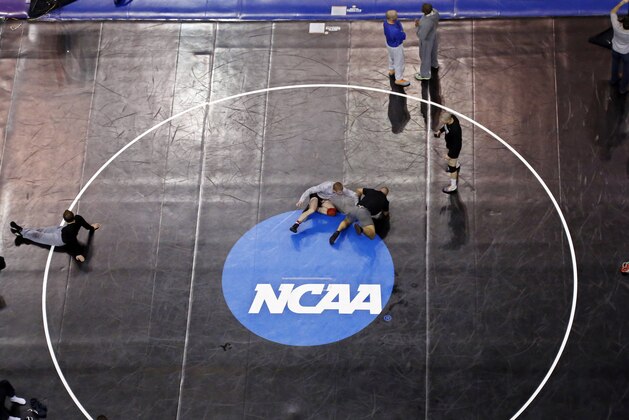 Donald Patrick, left, of Davidson College in Davidson, N.C., works with his coach, Brandon Sinnott, right, on a wrestling mat in Oklahoma City, Wednesday, March 19, 2014, in preparation for the NCAA college wrestling championships. Competition begins March 20. (AP Photo/Sue Ogrocki)