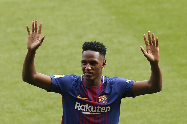 Barcelona's new signing Colombia's Yerry Mina gestures during his official presentation at the Camp Nou stadium in Barcelona, Spain, Saturday, Jan. 13, 2018. Mina took off his shoes and socks before stepping onto the field at Camp Nou Stadium during his official introduction to fans on Saturday. The gesture was an important first step for the defender arriving from Brazilian club Palmeiras. (AP Photo/Manu Fernandez) Barcelona's new signing Colombia's Yerry Mina gestures during his official presentation at the Camp Nou stadium in Barcelona, Spain, Saturday, Jan. 13, 2018. Mina took off his shoes and socks before stepping onto the field at Camp Nou Stadium during his official introduction to fans on Saturday. The gesture was an important first step for the defender arriving from Brazilian club Palmeiras. (AP Photo/Manu Fernandez)
