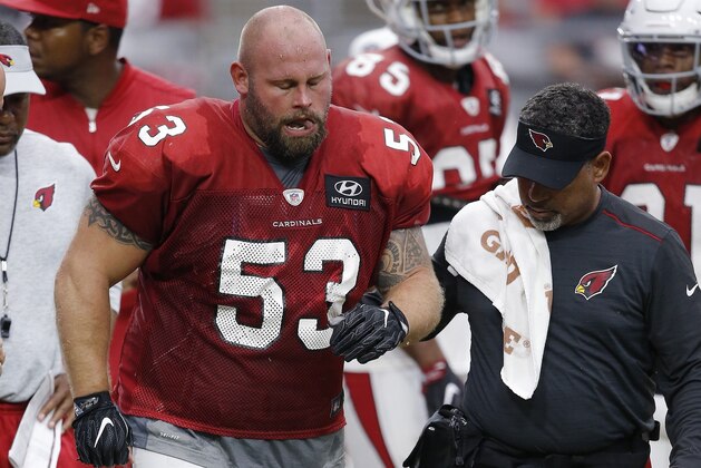 An injured Arizona Cardinals center A.Q. Shipley (53) is attended to by head athletic trainer Tom Reed, right, as Shipley walks off the field during an NFL football practice Saturday, Aug. 4, 2018, in Glendale, Ariz. (AP Photo/Ross D. Franklin)