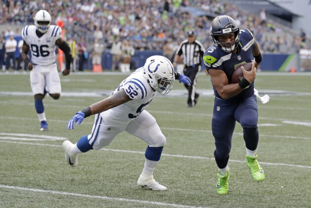 Seattle Seahawks quarterback Russell Wilson, right, scrambles with the ball as Indianapolis Colts linebacker Najee Goode (52) closes in during the first half of an NFL football preseason game, Thursday, Aug. 9, 2018, in Seattle. (AP Photo/Stephen Brashear)