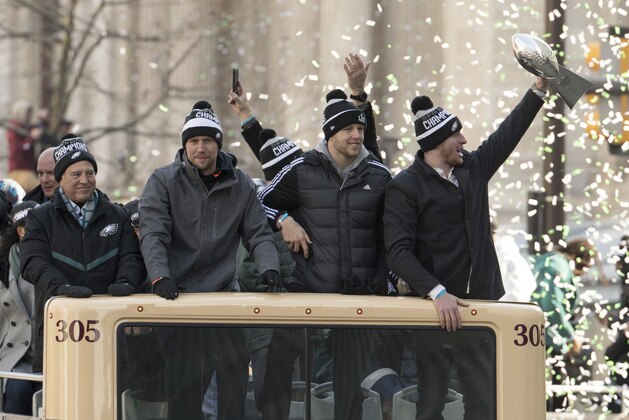 Philadelphia Eagles Carson Wentz, right, holds up the Vince Lombardi trophy as he rides with Nate Sudfeld, center right, Nick Foles, center left, and owner Jeffrey Lurie, left, during a Super Bowl victory parade, Thursday, Feb. 8, 2018, in Philadelphia. The Eagles beat the New England Patriots 41-33 in Super Bowl 52. (AP Photo/Christopher Szagola)
