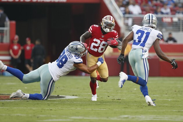 San Francisco 49ers running back Jerick McKinnon (28) runs between Dallas Cowboys defensive end Tyrone Crawford (98) and cornerback Byron Jones (31) during the first half of an NFL preseason football game in Santa Clara, Calif., Thursday, Aug. 9, 2018. (AP Photo/Tony Avelar)