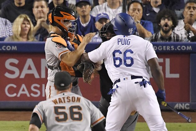 Los Angeles Dodgers' Yasiel Puig, right, shoves San Francisco Giants catcher Nick Hundley, left, as they argue while relief pitcher Tony Watson, below, runs in and home plate umpire Eric Cooper gets between them during the seventh inning of a baseball game, Tuesday, Aug. 14, 2018, in Los Angeles. (AP Photo/Mark J. Terrill)