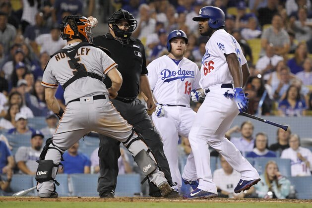 San Francisco Giants catcher Nick Hundley, left, reacts to being shoved by Los Angeles Dodgers' Yasiel Puig, right, as they argue while home plate umpire Eric Cooper, second from left, gets between them and Max Muncy runs in during the seventh inning of a baseball game, Tuesday, Aug. 14, 2018, in Los Angeles. (AP Photo/Mark J. Terrill)