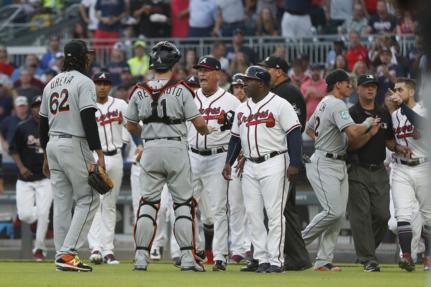 Miami Marlins catcher J.T. Realmuto (11) stands between pitcher Jose Urena (62) and Atlanta Braves manager Brian Snitker (43) as the dugouts empty after Urena hit Braves' Ronald Acuna Jr. with a pitch during the first inning of a baseball game Wednesday, Aug. 15, 2018m in Atlanta. Marlins' Derek Dietrich (32) and Braves' Ender Inciarte argue at right. (AP Photo/John Bazemore)