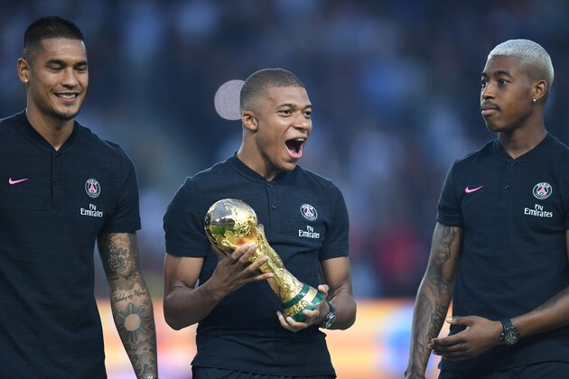 Paris Saint-Germain's French forward Kylian Mbappe (C) reacts as he holds the 2018 World Cup Trophy next to Paris Saint-Germain's French goalkeeper Alphonse Areola (L) and Paris Saint-Germain's French defender Presnel Kimpembe (R) prior to the French L1 football match between Paris Saint-Germain and Caen on August 12, 2018 at the Parc des Princes, in Paris. (Photo by Christophe ARCHAMBAULT / AFP)        (Photo credit should read CHRISTOPHE ARCHAMBAULT/AFP/Getty Images)