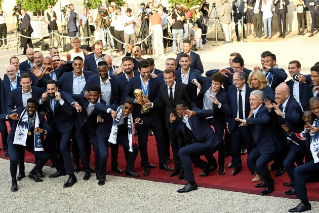 TOPSHOT - France's forward Olivier Giroud (3rdL), French president Emmanuel Macron, France's goalkeeper Hugo Lloris holding the trophy, France's midfielder Paul Pogba Brigitte Macron (3rdR), France's coach Didier Deschamps (2ndR) and other team members pose for a family photo  at a reception for the French national football team after they won the Russia 2018 World Cup final football match at the Elysee Presidential Palace on July 16, 2018 in Paris. - France celebrated their second World Cup win 20 years after their maiden triumph on July 15, 2018, overcoming a passionate Croatia side 4-2 in one of the most gripping finals in recent history. (Photo by Lionel BONAVENTURE / AFP)        (Photo credit should read LIONEL BONAVENTURE/AFP/Getty Images)