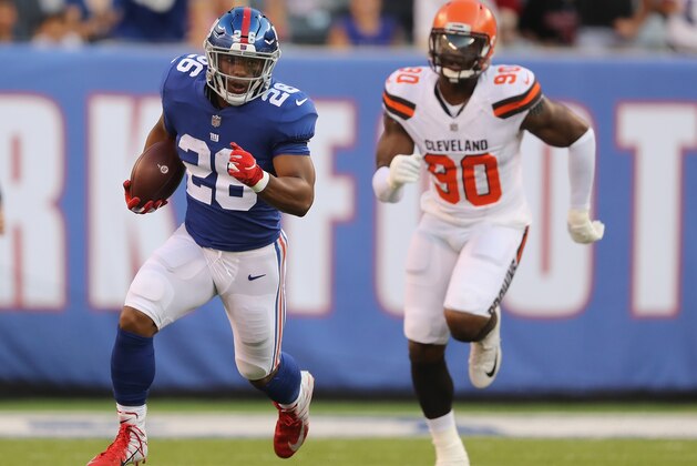 EAST RUTHERFORD, NJ - AUGUST 09:  Saquon Barkley #26 of the New York Giants carries the ball as Emmanuel Ogbah #90 of the Cleveland Browns in the first quarter during their preseason game on August 9,2018 at MetLife Stadium in East Rutherford, New Jersey.  (Photo by Elsa/Getty Images)