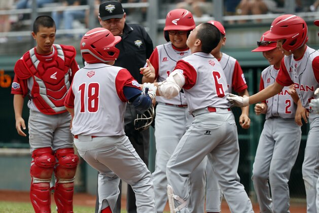 Japan's Shisei Fujimoto (18) is greeted at home by his teammates after his two-run home run off of Panama starting pitcher Adan Sanchez in the first inning home run of an International pool play baseball game at the Little League World Series tournament in South Williamsport, Pa., Sunday, Aug. 19, 2018. (AP Photo/Tom E. Puskar)