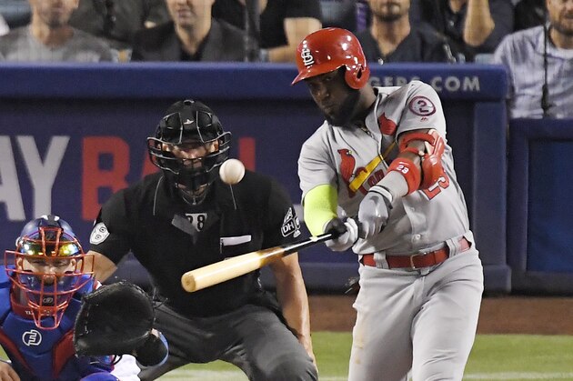 St. Louis Cardinals' Marcell Ozuna, right, hits a two-run home run as Los Angeles Dodgers catcher Yasmani Grandal, left, and home plate umpire Jim Wolf watch during the seventh inning of a baseball game, Tuesday, Aug. 21, 2018, in Los Angeles. (AP Photo/Mark J. Terrill)