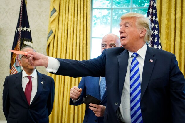 US President Donald Trump jokes with a red card after it was presented to him by FIFA President Gianni Infantino (C) during a meeting in the Oval Office of the White House in Washington, DC on August 28, 2018. Infantino offered Trump a set of yellow and red cards. - At center is FIFA President Gianni Infantino. (Photo by MANDEL NGAN / AFP)        (Photo credit should read MANDEL NGAN/AFP/Getty Images)