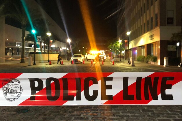 This photo shows a police car behind police tape blocking a street leading to the Jacksonville Landing area in downtown Jacksonville, Florida, August 26, 2018, where three people were killed, including the gunman, and 11 others wounded. - Two people were killed and 11 others wounded on August 26 when a video game tournament competitor went on a shooting rampage before turning the gun on himself in the northern Florida city of Jacksonville, local police said. Sheriff Mike Williams named the suspect of the shooting at a Madden 19 American football eSports tournament as 24-year-old David Katz from Baltimore, Maryland. (Photo by Gianrigo MARLETTA / AFP)        (Photo credit should read GIANRIGO MARLETTA/AFP/Getty Images)