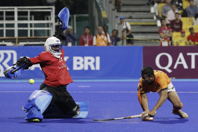 India's goalkeeper Sreejesh Parattu Raveendran, left, tries to block a shot from Malaysia's Muhammad Firhan during their men's hockey semi-final match at the 18th Asian Games in Jakarta, Indonesia, Thursday, Aug. 30, 2018. (AP Photo/Aaron Favila)