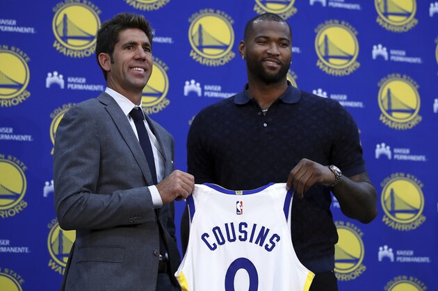 Golden State Warriors General Manager Bob Myers, left, holds a jersey with DeMarcus Cousins during a media conference Thursday, July 19, 2018, in Oakland, Calif. Cousins signed a one-year, $5.3M deal with the defending champion Warriors. (AP Photo/Ben Margot)
