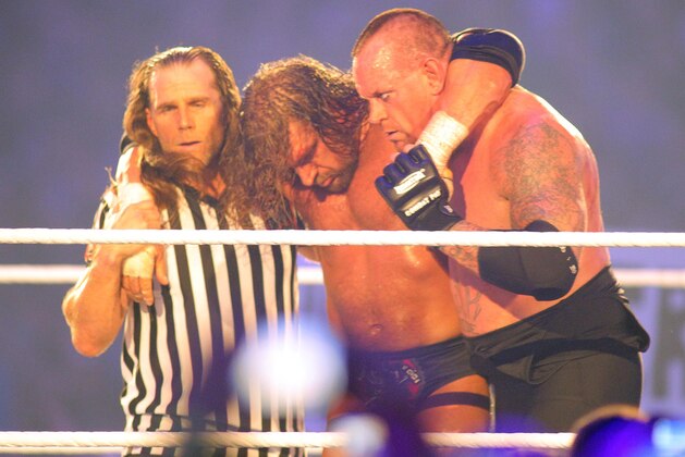 COMMERCIAL IMAGE - In this photograph taken by AP Images for WWE, Hall of famer Shawn Michaels, left, and Undertaker who brings his un-defeated record to 20-0, right, take H.H.H. from the ring during WrestleMania XXVIII in Sun Life Stadium on Sunday, April 1, 2012 in Miami. (Marc Serota/AP Images for WWE)