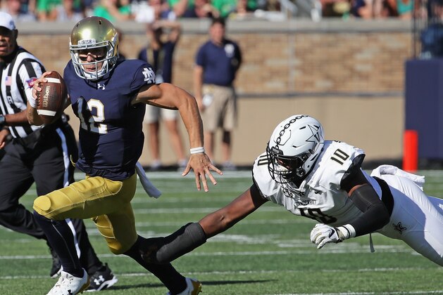 SOUTH BEND, IN - SEPTEMBER 15:  Ian Book #12 of the Notre Dame Fighting Irish breaks away from  Dayo Odeyingbo #10 of the Vanderbilt Commodores
at Notre Dame Stadium on September 15, 2018 in South Bend, Indiana.  (Photo by Jonathan Daniel/Getty Images)