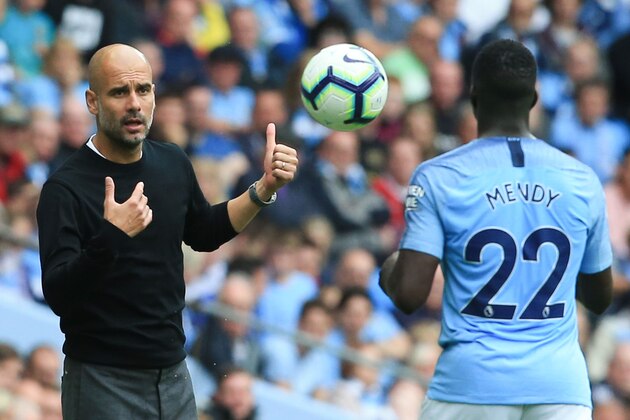 Manchester City's Spanish manager Pep Guardiola (L) throws the ball to Manchester City's French defender Benjamin Mendy (R) during the English Premier League football match between Manchester City and Huddersfield Town at the Etihad Stadium in Manchester, north west England, on August 19, 2018. (Photo by Lindsey PARNABY / AFP) / RESTRICTED TO EDITORIAL USE. No use with unauthorized audio, video, data, fixture lists, club/league logos or 'live' services. Online in-match use limited to 120 images. An additional 40 images may be used in extra time. No video emulation. Social media in-match use limited to 120 images. An additional 40 images may be used in extra time. No use in betting publications, games or single club/league/player publications. /         (Photo credit should read LINDSEY PARNABY/AFP/Getty Images)