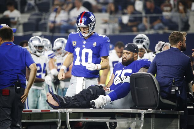 New York Giants quarterback Eli Manning (10) checks on offensive guard Jon Halapio (75) as he is carted off the field during the second half of an NFL football game against the Dallas Cowboys in Arlington, Texas, Sunday, Sept. 16, 2018. (AP Photo/Michael Ainsworth)