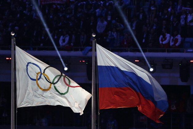 FILE - In this Feb. 23, 2014 file photo the Russian national flag, right, flies after it is hoisted next to the Olympic flag during the closing ceremony of the 2014 Winter Olympics in Sochi, Russia.  On Monday, July 18, 2016 a report on Russian doping by investigator Richard McLaren is to be released in Toronto.  (AP Photo/Matthias Schrader, file)