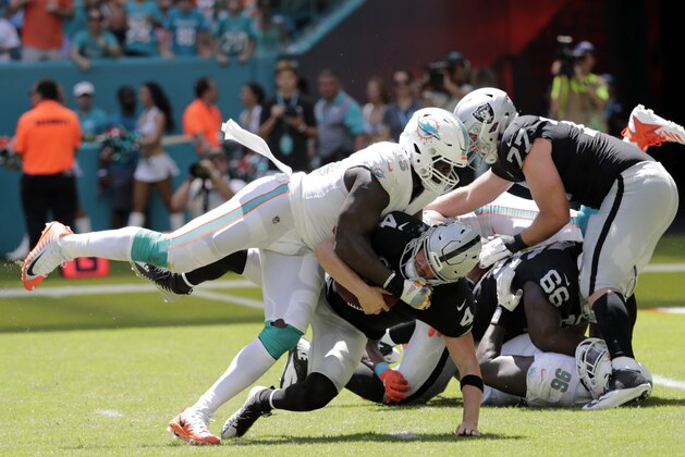 FILE - In this Sunday, Sept. 23, 2018, file photo, Miami Dolphins defensive end William Hayes (95) sacks Oakland Raiders quarterback Derek Carr (4) during the first half of an NFL football game, in Miami Gardens, Fla. The NFL is getting roughed up over its amplified enforcement of roughing the passer penalties that has produced head-scratching, game-changing calls and a season-ending injury to a defender trying to comply with the league’s mandate not to land on the quarterback. Hayes tore his right ACL trying to avoid landing on Carr. (AP Photo/Lynne Sladky, File)