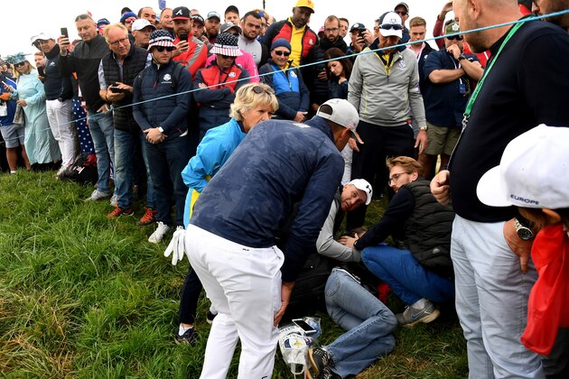 US golfer Brooks Koepka (C) reacts next to an injured spectator who fell  during the fourball match on the first day of the 42nd Ryder Cup at Le Golf National Course at Saint-Quentin-en-Yvelines, south-west of Paris on September 28, 2018. (Photo by FRANCK FIFE / AFP)        (Photo credit should read FRANCK FIFE/AFP/Getty Images)