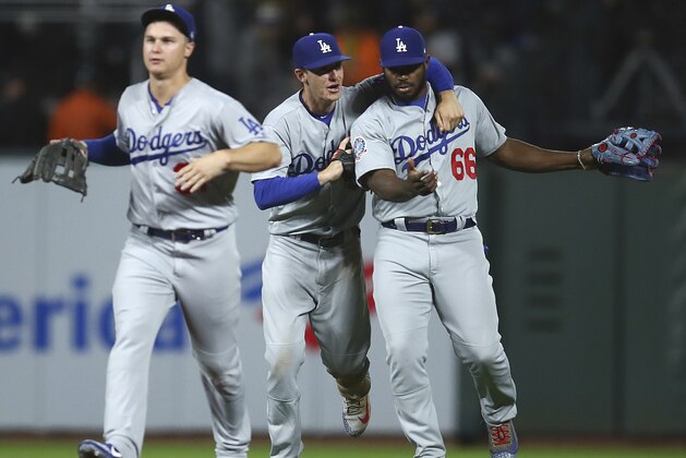 From left, Los Angeles Dodgers' Joc Pederson, Cody Bellinger, and Yasiel Puig (66) celebrate the 3-1 win over the San Francisco Giants at the end of a baseball game Friday, Sept. 28, 2018, in San Francisco. (AP Photo/Ben Margot)