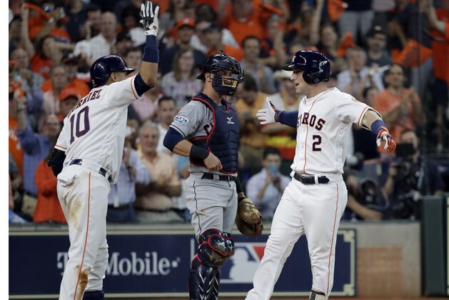Houston Astros' Alex Bregman (2) celebrates his solo home run with teammate Yuli Gurriel (10) as Cleveland Indians catcher Yan Gomes, center, looks on during the fourth inning in Game 1 of an American League Division Series baseball game against the Cleveland Indians, Friday, Oct. 5, 2018, in Houston. (AP Photo/David J. Phillip)