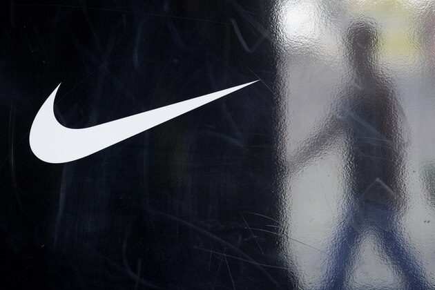 In this Sept. 21, 2010 photograph, a Nike logo is seen on a window at the Nike Factory Store in San Diego, as a man's reflection passes at right. Nike reports quarterly financial results Thursday, Sept. 23, 2010, after the market close. (AP Photo/Gregory Bull)