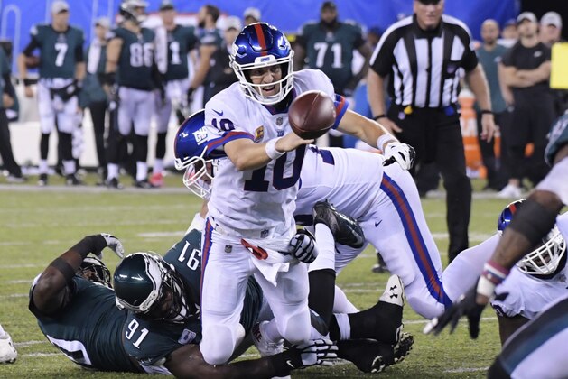 New York Giants quarterback Eli Manning (10) throws gets rid of the ball as he is tackled by Philadelphia Eagles' Fletcher Cox (91) during the second half of an NFL football game Thursday, Oct. 11, 2018, in East Rutherford, N.J. The Eagles won 34-13. (AP Photo/Bill Kostroun)
