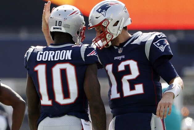 New England Patriots quarterback Tom Brady smiles at and taps the helmet of wide receiver Josh Gordon before an NFL football game against the Miami Dolphins at Gillette Stadium, Sunday, Sept. 30, 2018 in Foxborough, Mass. (Winslow Townson/AP Images for Panini)
