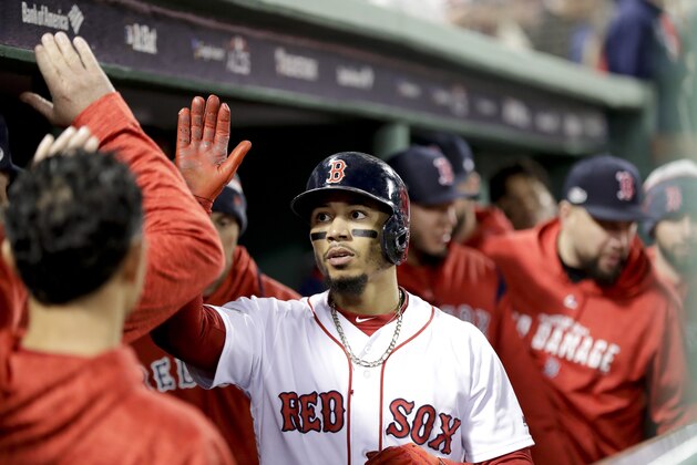 Boston Red Sox's Mookie Betts celebrates in the dugout after scoring on a single by Andrew Benintendi during the first inning in Game 2 of a baseball American League Championship Series against the Houston Astros on Sunday, Oct. 14, 2018, in Boston. (AP Photo/David J. Phillip)