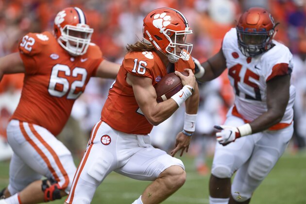 Clemson quarterback Trevor Lawrence scrambles out of the pocket with blocking help from Cade Stewart (62) as Syracuse's Kenneth Ruff chaes during the first half of an NCAA college football game Saturday, Sept. 29, 2018, in Clemson, S.C. Clemson won 27-23. (AP Photo/Richard Shiro)