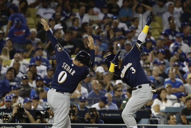 Milwaukee Brewers' Orlando Arcia celebrates his two-run home run with third base coach Ed Sedar during the seventh inning of Game 3 of the National League Championship Series baseball game against the Los Angeles Dodgers Monday, Oct. 15, 2018, in Los Angeles. (AP Photo/Matt Slocum)
