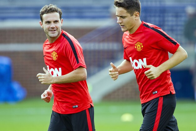 Manchester United midfielders Juan Mata, left, and Ander Herrera jog during a training session, Friday, Aug. 1, 2014, at Michigan Stadium in Ann Arbor, Mich. Real Madrid will face Manchester United in a Guinness International Champions Cup match Saturday at this college football stadium. (AP Photo/Tony Ding)