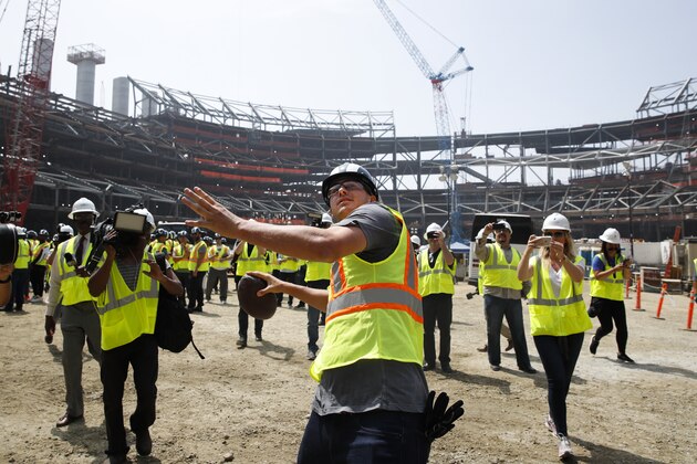 FILE - In this June 14, 2018, file photo, Los Angeles Rams quarterback Jared Goff throws the ball to construction workers while visiting the team's new NFL football stadium, in Inglewood, Calif. Although the palatial Inglewood NFL stadium is still nearly two years from completion, the Los Angeles Rams and Los Angeles Chargers are ready to fill it up. The Rams will begin season ticket sales in two weeks for more than 50,000 seats in the under-construction stadium at Hollywood Park, COO Kevin Demoff announced Thursday, Sept. 6, 2018. (AP Photo/Jae C. Hong, File)