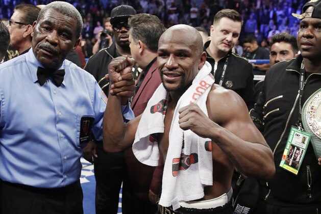Floyd Mayweather Jr. poses for photographers after defeating Conor McGregor in a super welterweight boxing match Saturday, Aug. 26, 2017, in Las Vegas. (AP Photo/Isaac Brekken)