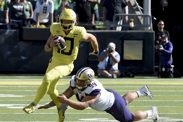 EUGENE, OR - OCTOBER 13:  Quarterback Justin Herbert #10 of the Oregon Ducks scrambles against defensive lineman Greg Gaines #99 of the Washington Huskies in the first half of the game at Autzen Stadium on October 13, 2018 in Eugene, Oregon.  (Photo by Steve Dykes/Getty Images)