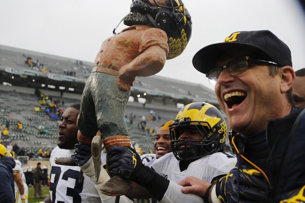 CORRECTS IDENITY OF PLAYER AT LEFT TO MICHIGAN DEFENSIVE LINEMAN LAWRENCE MARSHALL (93) INSTEAD OF MICHIGAN TIGHT END ZACH GENTRY (83) - Michigan defensive lineman Lawrence Marshall (93), linebacker Devin Bush, and head coach Jim Harbaugh walk off the field with the Paul Bunyan trophy after an NCAA college football game against Michigan State, Saturday, Oct. 20, 2018, in East Lansing, Mich. Michigan won 21-7. (AP Photo/Carlos Osorio) CORRECTS IDENITY OF PLAYER AT LEFT TO MICHIGAN DEFENSIVE LINEMAN LAWRENCE MARSHALL (93) INSTEAD OF MICHIGAN TIGHT END ZACH GENTRY (83) - Michigan defensive lineman Lawrence Marshall (93), linebacker Devin Bush, and head coach Jim Harbaugh walk off the field with the Paul Bunyan trophy after an NCAA college football game against Michigan State, Saturday, Oct. 20, 2018, in East Lansing, Mich. Michigan won 21-7. (AP Photo/Carlos Osorio)