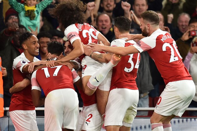 Arsenal's Gabonese striker Pierre-Emerick Aubameyang (L) celebrates with teammates after scoring their third goal during the English Premier League football match between Arsenal and Leicester City at the Emirates Stadium in London on October 22, 2018. (Photo by Glyn KIRK / IKIMAGES / AFP) / RESTRICTED TO EDITORIAL USE. No use with unauthorized audio, video, data, fixture lists, club/league logos or 'live' services. Online in-match use limited to 45 images, no video emulation. No use in betting, games or single club/league/player publications.        (Photo credit should read GLYN KIRK/AFP/Getty Images)
