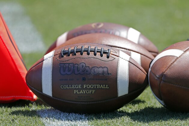 FILE - In this Sept. 2, 2017, file photo, footballs sit on the turf ready for kick-off before the start of an NCAA football game between South Carolina and North Carolina State in Charlotte, N.C. A study from The Institute for Diversity and Ethics (TIDES) finds that white men still “overwhelmingly” fill leadership positions at top-level college sports programs and conferences, leaving a “consistent underrepresentation of women and people of color” in those roles. (AP Photo/Bob Leverone, File)