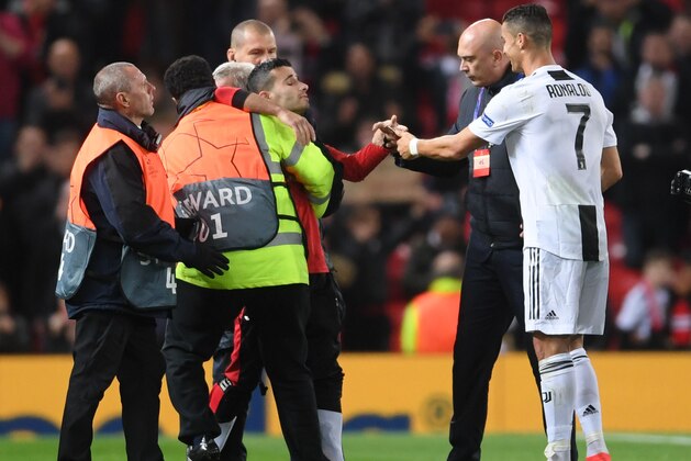 MANCHESTER, ENGLAND - OCTOBER 23: Cristiano Ronaldo of Juventus hands a mobile phone to a pitch invader after taking a selfie with him after the Group H match of the UEFA Champions League between Manchester United and Juventus at Old Trafford on October 23, 2018 in Manchester, United Kingdom. (Photo by Laurence Griffiths/Getty Images)