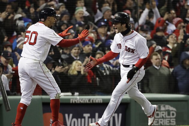Boston Red Sox's Andrew Benintendi celebrates with Boston Red Sox's Mookie Betts after scoring with Betts on a two run RBI single by J.D. Martinez during the fifth inning of Game 2 of the World Series baseball game against the Los Angeles Dodgers Wednesday, Oct. 24, 2018, in Boston. (AP Photo/David J. Phillip)