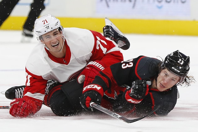 Detroit Red Wings center Dylan Larkin (71) and Carolina Hurricanes left wing Brock McGinn (23) hit the ice in the first period of an NHL hockey game Monday, Oct. 22, 2018, in Detroit. Larking was called for a tripping penalty. (AP Photo/Paul Sancya)