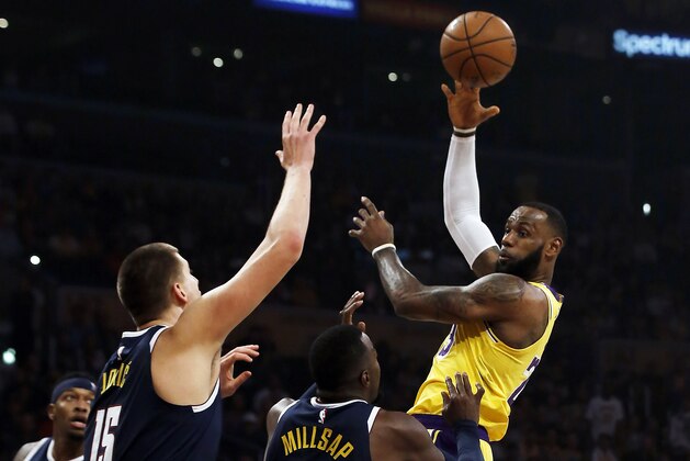 Los Angeles Lakers forward LeBron James, right, passes over Denver Nuggets center Nikola Jokic (15), of Serbia, and forward Paul Millsap (4) during the first half of an NBA basketball game in Los Angeles, Thursday, Oct. 25, 2018. (AP Photo/Alex Gallardo)