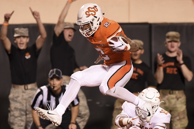 Oklahoma State wide receiver Tylan Wallace (2) jumps across the goal line while evading Texas defensive back Brandon Jones (19) in the first half of an NCAA college football game in Stillwater, Okla., Saturday, Oct. 27, 2018. (AP Photo/Brody Schmidt)