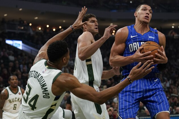 Orlando Magic's Aaron Gordon is fouled driving between Milwaukee Bucks' Brook Lopez and Giannis Antetokounmpo during the first half of an NBA basketball game Saturday, Oct. 27, 2018, in Milwaukee. (AP Photo/Morry Gash)